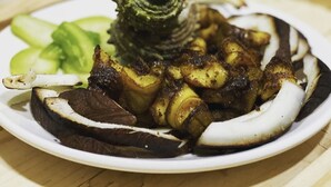 A plate of food with grilled meat, vegetables, and a decorative item.