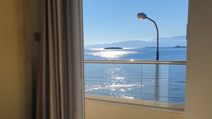 Une chambre avec un lit, une vue sur la mer et une balustrade de balcon.