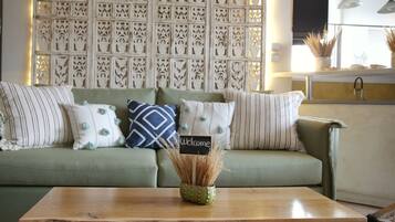 A green sofa with striped pillows, a wooden coffee table, and a decorative wall with intricate patterns.