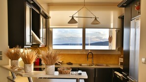 Une cuisine moderne dotée d’une grande fenêtre, de deux suspensions et offrant une vue sur la mer.