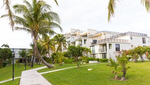 A modern hotel with multiple floors, outdoor pathways, and palm trees. - Stunning Oceanfront Condo at Coral Beach unit 1107 (Freeport)