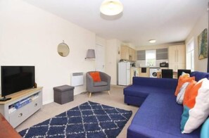 A compact living space with a television, sofa, and a small kitchen area. - Hidden Gem of Newark (New Ollerton)