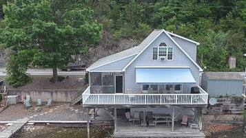 Une maison à deux étages avec un balcon, une jetée et une petite terrasse.