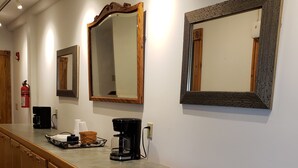 Quarto de hotel com cozinha compacta, máquina de café e espelho.