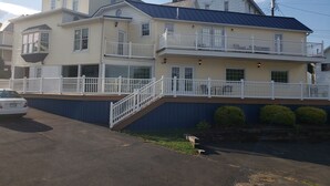 Uma casa de dois andares com uma varanda no primeiro andar e uma varanda no segundo andar com guarda-corrimão branco.