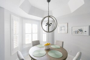 A dining area with a round table, green placemats, and a bowl of lemons.