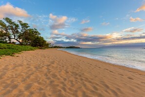 A sandy beach with a clear sky and a distant view of a coastline.