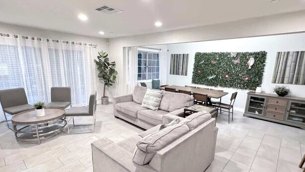 A modern living room with a sofa, chairs, a dining table, and a kitchen area. - Rainforest 4BR Pool Villa - Walk to Disneyland (Anaheim)