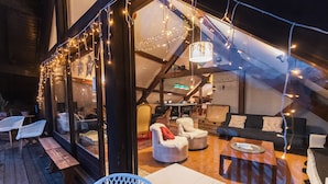 Un interior con cubierta de madera, asientos blancos acolchados e iluminación con luces colgantes.