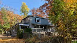 Ein zweigeschossiges Haus mit Veranda, umgeben von Herbstlaub.
