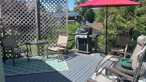 Eine Terrasse mit Gartenmöbeln, einem Grill und einem roten Sonnenschirm.
