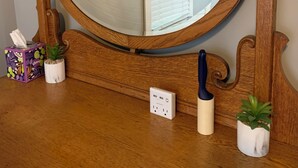 Ein spiegel mit Holzrahmen in runder Form, eine kleine Topfpflanze, eine Papiertauschbox und ein Messer auf einer Holztischplatte.