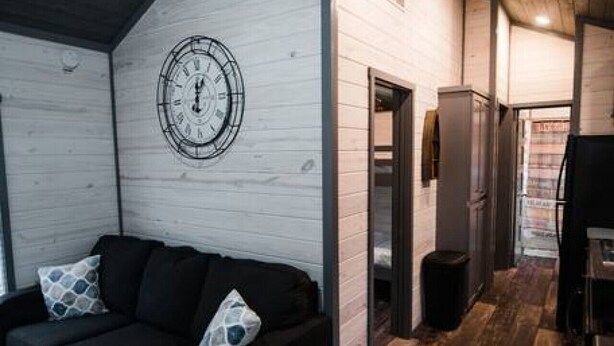 A modern interior with a black sofa, a wooden ceiling, and a clock on the wall.