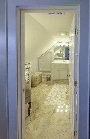 Enter a bathroom with a white vanity, sink, and mirror, set against a backdrop of patterned tiles.