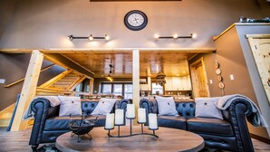 A cozy living room with a black leather sofa, a round coffee table, and a fireplace. - Gorgeous Luxury Cabin! 360 Views, Fire Pit, Theater Room - Prime Location!  (Gatlinburg)