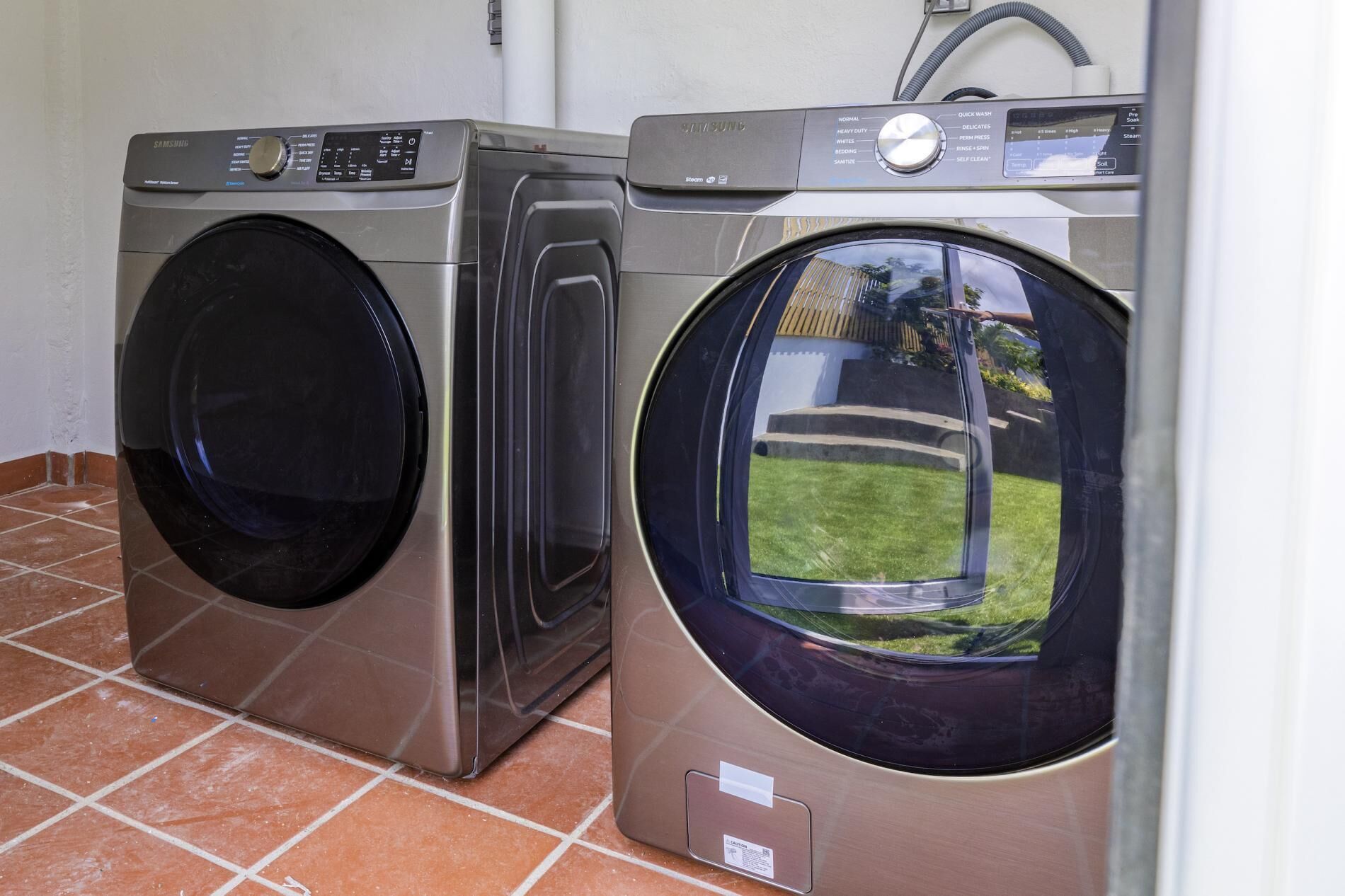 Due lavatrici a carica frontale in acciaio inox in una lavanderia con pavimento piastrellato.