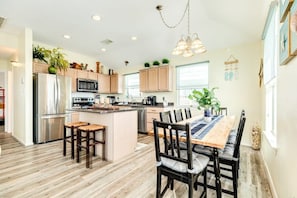 Una cocina moderna con armarios de madera, electrodomésticos de acero inoxidable y un comedor con mesa y sillas de madera.
