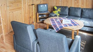 A cozy room with a sofa, chairs, a small table with a plaid tablecloth, a television, and a lamp. - Awesome home in Spangereid with kitchen (Spangereid)