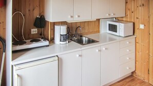A compact kitchen with white cabinets, a microwave, a coffee maker, and a dishwasher. - Awesome home in Spangereid with kitchen (Spangereid)