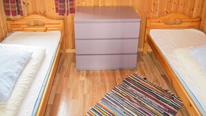 A wooden cabin room with two beds, a small dresser, and a colorful striped rug. - Awesome home in Spangereid with kitchen (Spangereid)