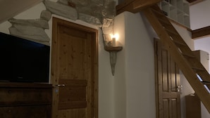 Eine Holztür mit einer Steinsäule, einer Wandleuchte und einer Treppe.
