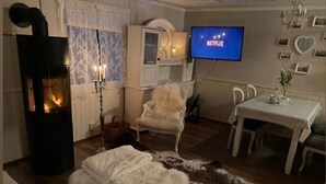Un salon chaleureux avec une cheminée, un téléviseur diffusant du contenu « NETFLIX », et un coin repas.