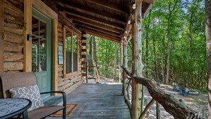 Eine Holzjagdhaus mit Veranda, einer Bank und einem Tisch.
