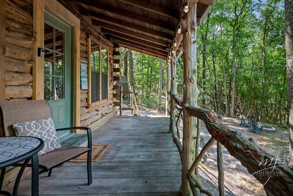A wooden cabin with a porch, a bench, and a table.