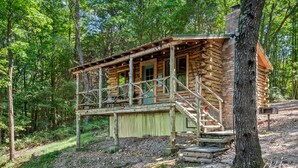Eine rustikale Holzblockhütte mit einer Holzdiele und Treppe zum Eingang.