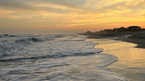 Een strand met golven en een ondergaande zon.