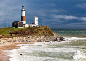 A lighthouse with a white and brown structure, situated on a grassy cliff overlooking the sea. - NEW LISTING - Newly Renovated Beach Home - Short Walk to Beach and Town (Montauk)