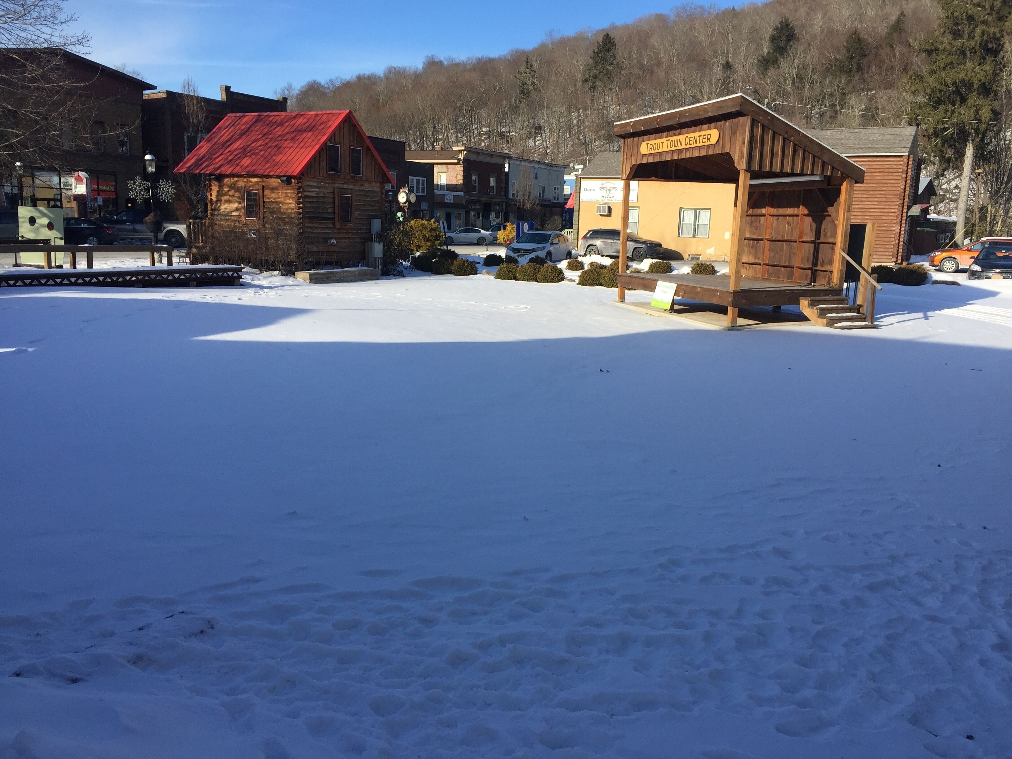 Centro de uma cidade coberta de neve, com edifícios de madeira, incluindo uma placa para Trout Town Center.