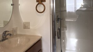 Un baño con lavamanos, espejo y ducha.