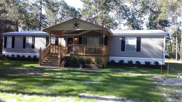 Uma casa móvel com varanda, escadas e um deck.