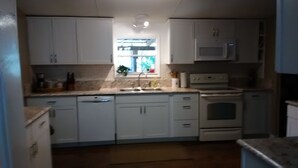 Uma cozinha compacta com armários brancos, micro-ondas embutido e pia.