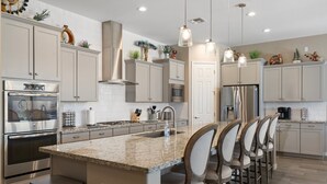 A modern kitchen with granite countertops, stainless steel appliances, and a central island with bar stools. - No Fee Heated pool & Spa  gorgeous House.  (Goodyear)