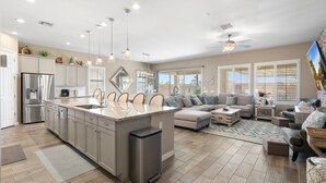 A spacious kitchen with a central island, stainless steel appliances, pendant lighting, and a large window providing natural light. - No Fee Heated pool & Spa  gorgeous House.  (Goodyear)