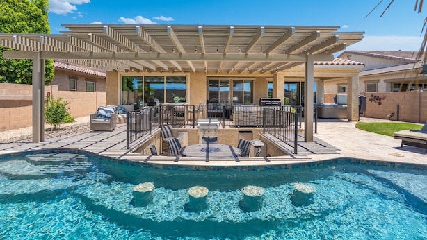 A swimming pool with a covered patio area, lounge chairs, and a grill. - No Fee Heated pool & Spa  gorgeous House.  (Goodyear)