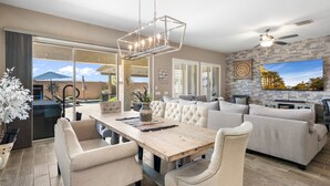 A spacious living area with a wooden dining table, beige sofas, and a stone accent wall. - No Fee Heated pool & Spa  gorgeous House.  (Goodyear)