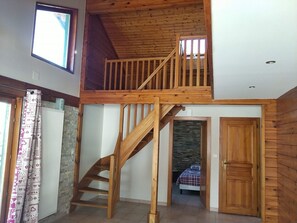 A two-story wooden staircase leading to a loft bedroom with a stone wall and a bed. - Mountain cabin for 12 people near Gérardmer (Gerbépal)