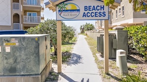 A sign for Barefoot Beach Resort with a pathway leading to the beach.