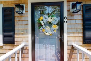 Stunning front entrance with a welcoming floral wreath, glass panel, and black shutters.
