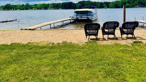 A lakeside view with a dock, chairs, and a row of boats. - The Perfect Lake Getaway! (Paw Paw)