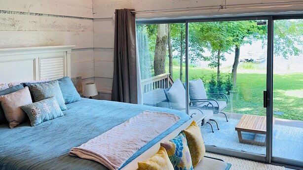 A bedroom with a large bed, a ceiling fan, and a view of the outdoors through a sliding glass door. - The Perfect Lake Getaway! (Paw Paw)