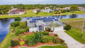 A house with solar panels, a flag, and a well-maintained garden.