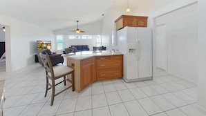 A spacious kitchen with a central island, wooden cabinets, and a white refrigerator.