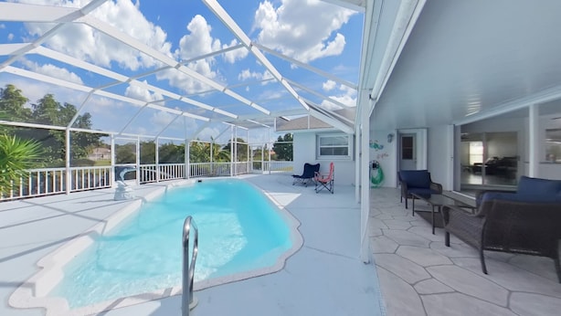 A covered outdoor swimming pool with lounge chairs and a patio area.