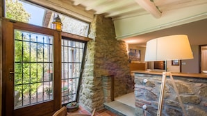 A stone fireplace with a wooden bench, a door with a metal gate, and a lamp on a table.