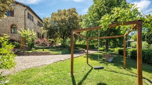 A garden with a swing set, a stone building, and a well-maintained lawn.