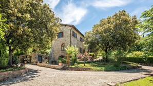 A stone building with a gravel driveway, surrounded by trees and a well-maintained garden.